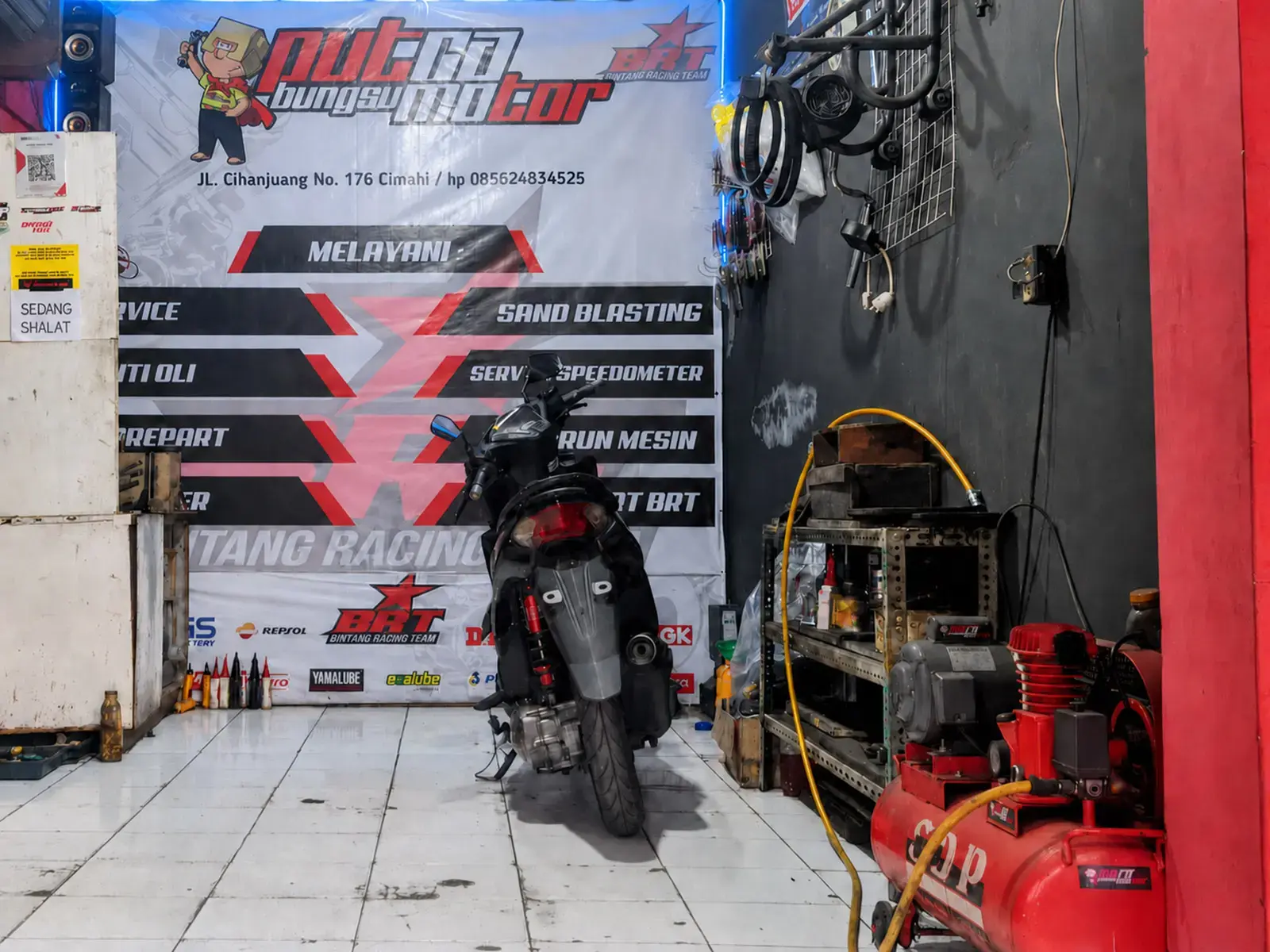 Area kerja Putra Bungsu Motor dengan sepeda motor dan peralatan bengkel.